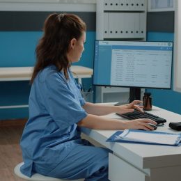 Woman working as nurse with computer and documents