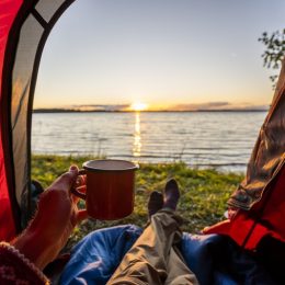 Man camping in Estonia, watching sunset lying in tent