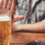 Man declining a beer on the table.