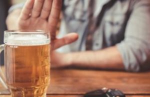 Man declining a beer on the table.