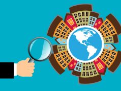 Image of apartments on a globe with a hand holding a magnifying glass.