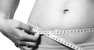 Woman measuring her waist.